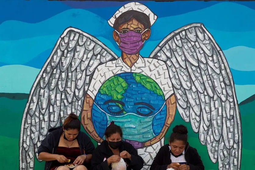 Tres mujeres descansan frente a un mural dedicado al personal de la salud el 11 de marzo de 2021, en Tegucigalpa (Honduras). EFE/Gustavo Amador