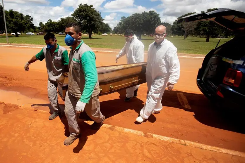 Trabajadores cargan un féretro con una víctima mortal de covid-19 rumbo a su entierro en el cementerio Campo da Esperança, en Brasilia (Brasil).